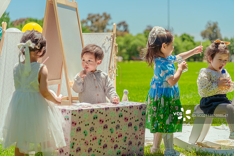 公园草坪白纱帐画板前交流互动的四个小伙伴图片素材