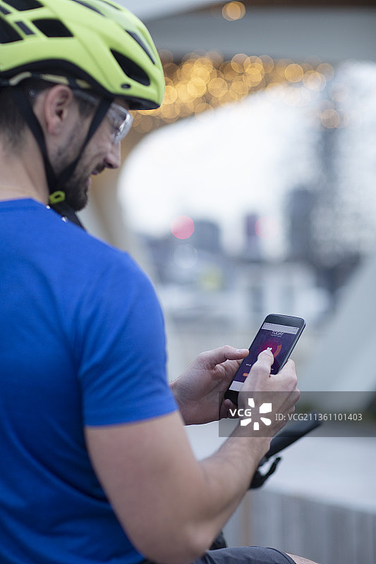戴着自行车头盔使用智能手机的男人图片素材