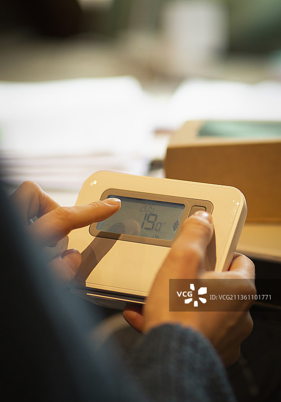 女人正在调节智能家居温控器图片素材