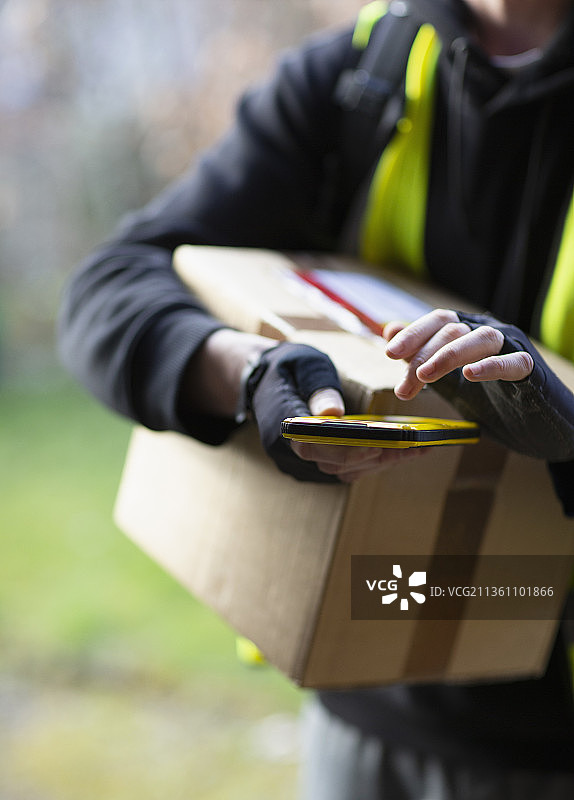 使用智能手机送包裹的快递员图片素材