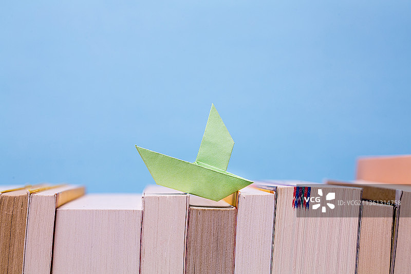 书海泛舟，一排书上的折纸小帆船图片素材