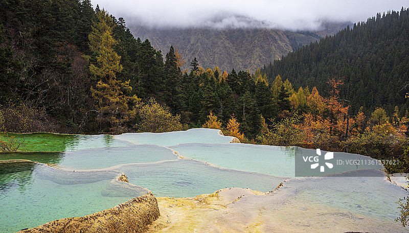 四川黄龙风景区清澈的池水，秋天黄绿相间的森林和高山的云雾，构成了一幅美丽的森林之镜。图片素材