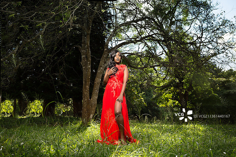 在内罗毕肯尼亚的田野上，身穿红色连衣裙的年轻女子户外肖像图片素材