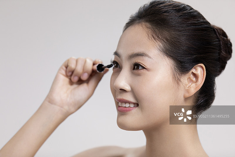漂亮的年轻女子涂睫毛膏图片素材