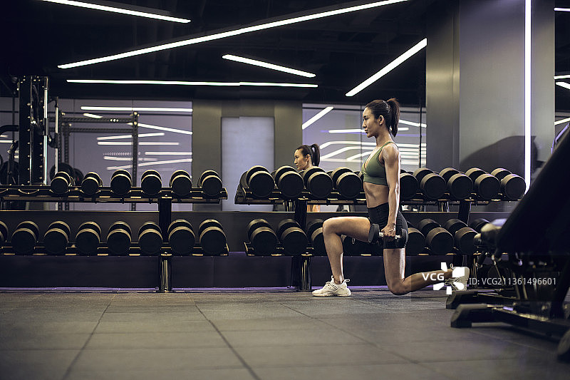 年轻女士在健身房举哑铃图片素材