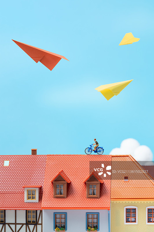 微缩创意蓝天白云欧洲建筑屋顶上骑单车的少年图片素材