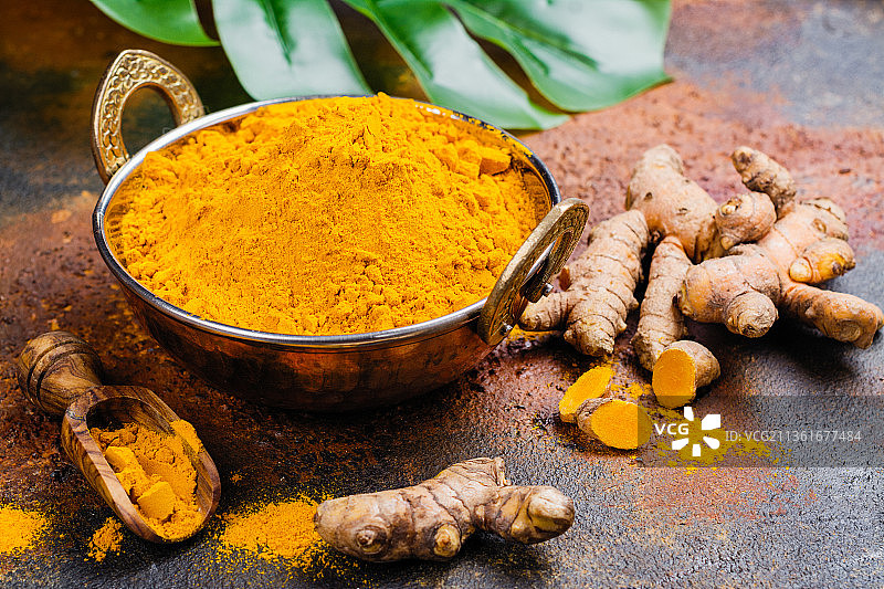 粗糙背景上的姜黄粉和新鲜姜黄根图片素材