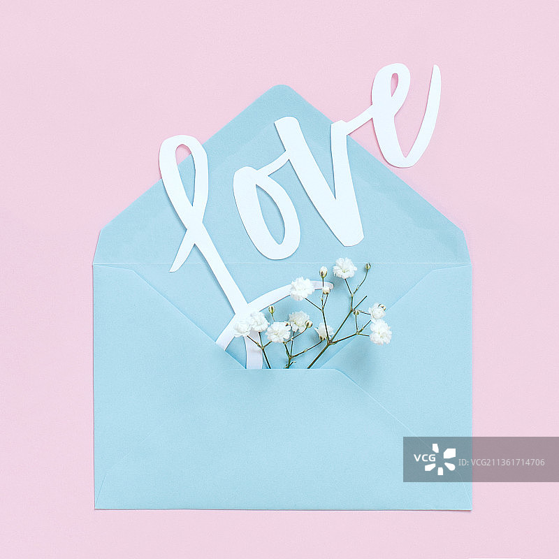 浅粉色背景上的花朵、信封和LOVE字样俯视图图片素材
