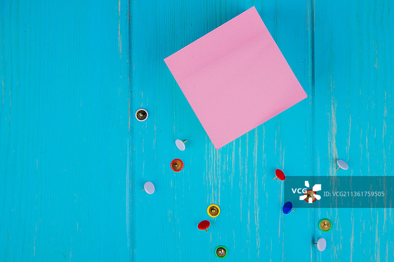 蓝色背景上的便签纸和图钉顶视图图片素材
