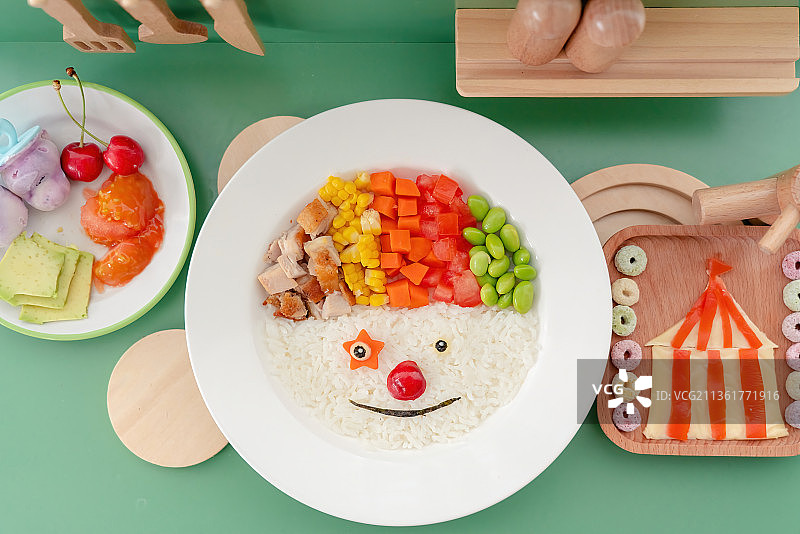 绿色灶台上的小丑饭甜圈小丑帽面包红樱桃牛油果奶酪图片素材