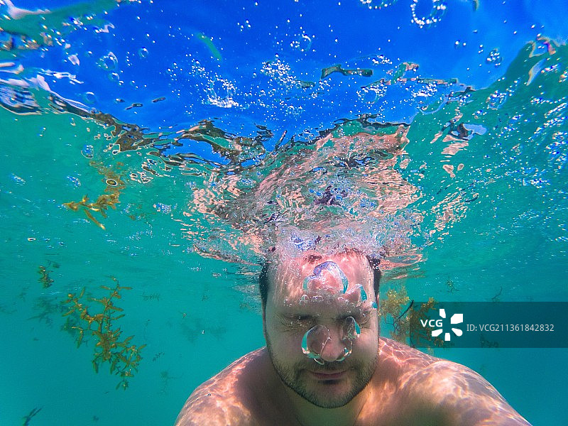 蓝色色调：在海中游泳的赤膊男人图片素材