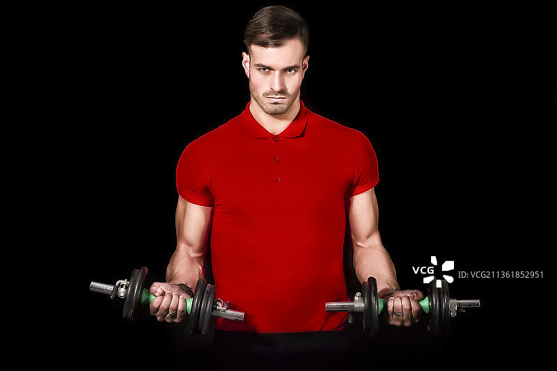 私人教练，男子在意大利里米尼举哑铃（黑色背景）图片素材