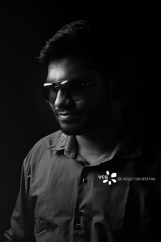 录音室单色人像：戴眼镜的年轻男人，黑色背景图片素材