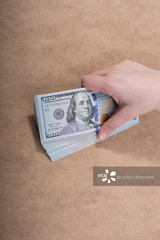 手持美元，隔离在木制背景上图片素材