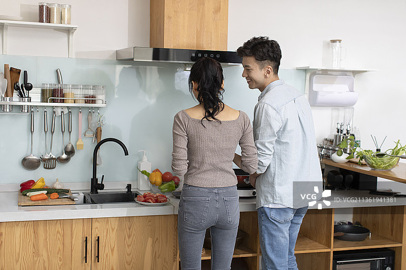 快乐的年轻夫妇在厨房做饭图片素材