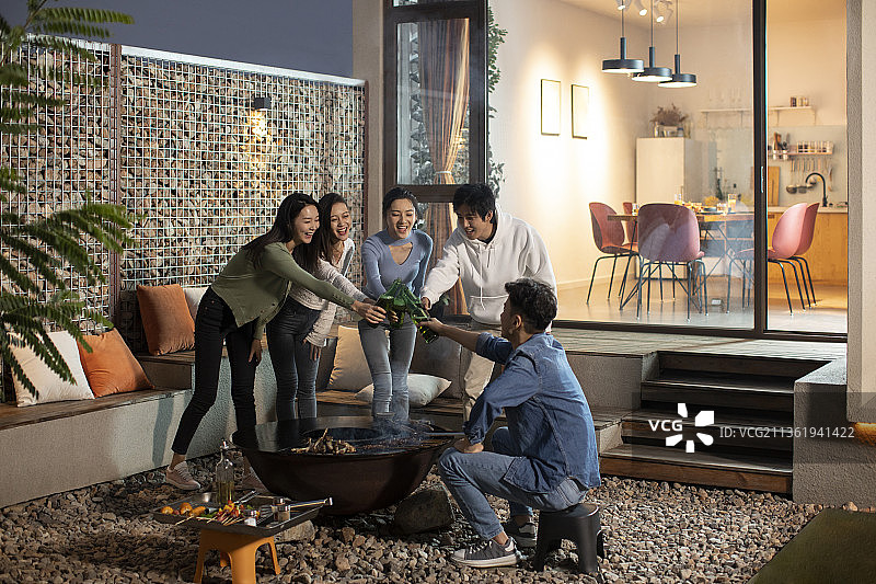 年轻朋友在庭院里烧烤聚餐图片素材