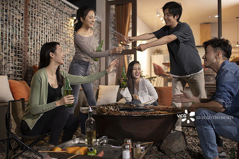 年轻朋友在庭院里烧烤聚餐图片素材