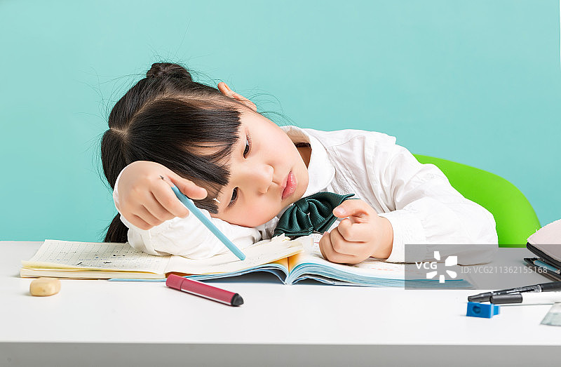 写作业的小学生趴在桌上抠手指图片素材