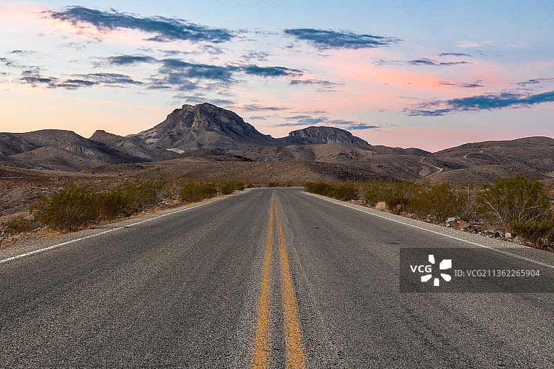 日落时分通往内华达州克拉克县群山的空旷道路图片素材
