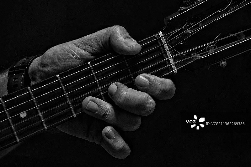 弹奏：在黑色背景下弹吉他的手图片素材