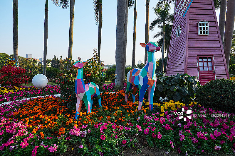 广州云台花园里蓝天下花丛中彩色风车旁的装饰品彩色小鹿图片素材