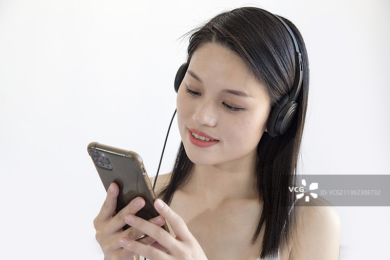 长头发的女人一边听音乐一边使用手机图片素材