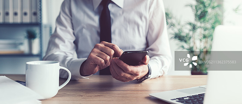 商务沟通概念，塞尔维亚办公室里使用手机的商人图片素材