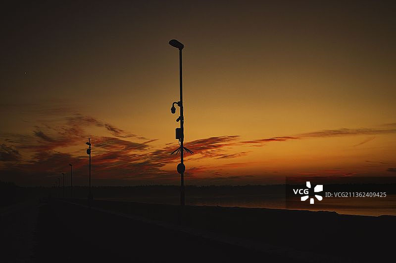 冬季日落：波兰日落时分天空中的路灯剪影图片素材