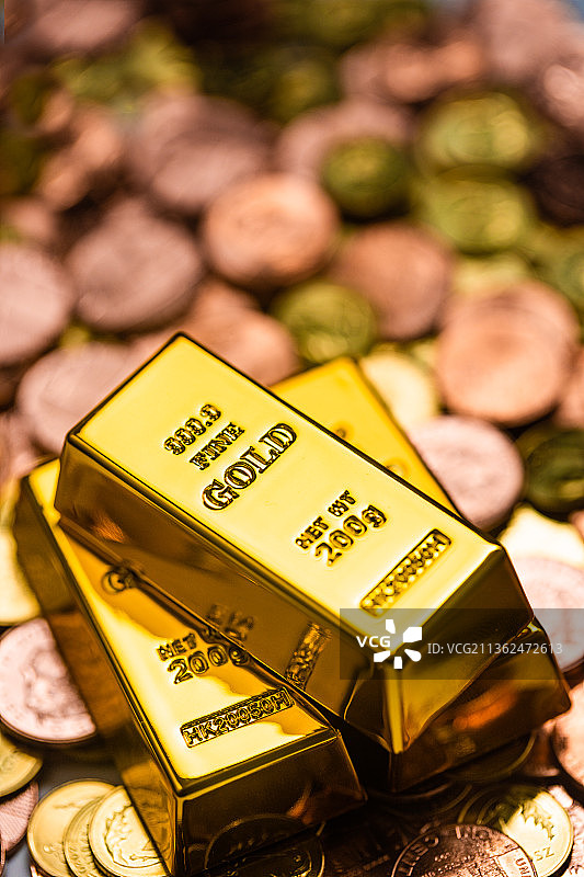灯光下的一堆硬币上叠放着三根金条图片素材