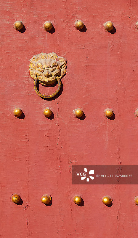 中国山东泰安著名景点泰山风景区岱庙行宫里城墙门上的金黄色的狮子门环和门钉图片素材