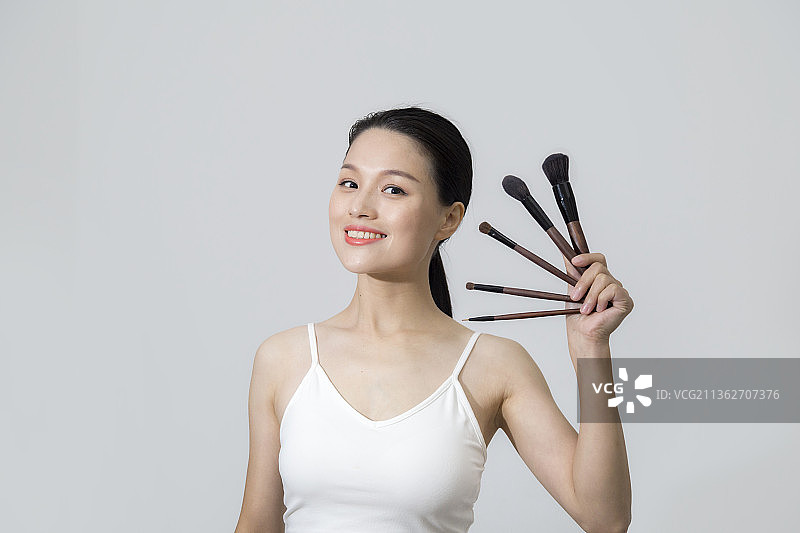 一个东方美女拿着化妆笔上半身特写图片素材