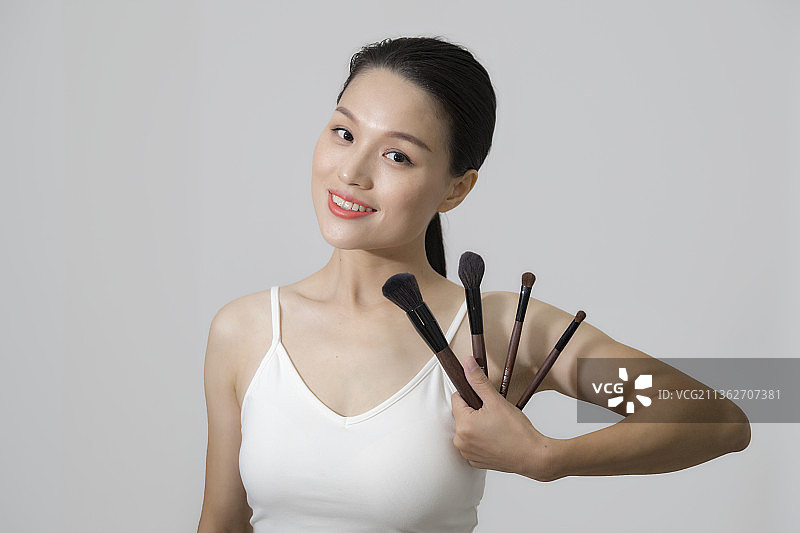 一个东方美女拿着化妆笔上半身特写图片素材