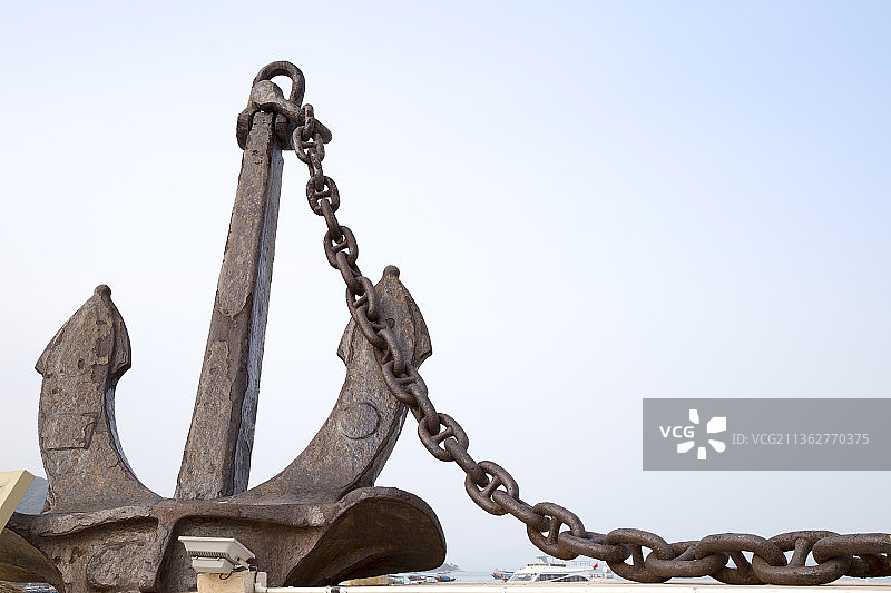 蓝色天空背景下一个破旧的铁锚图片素材