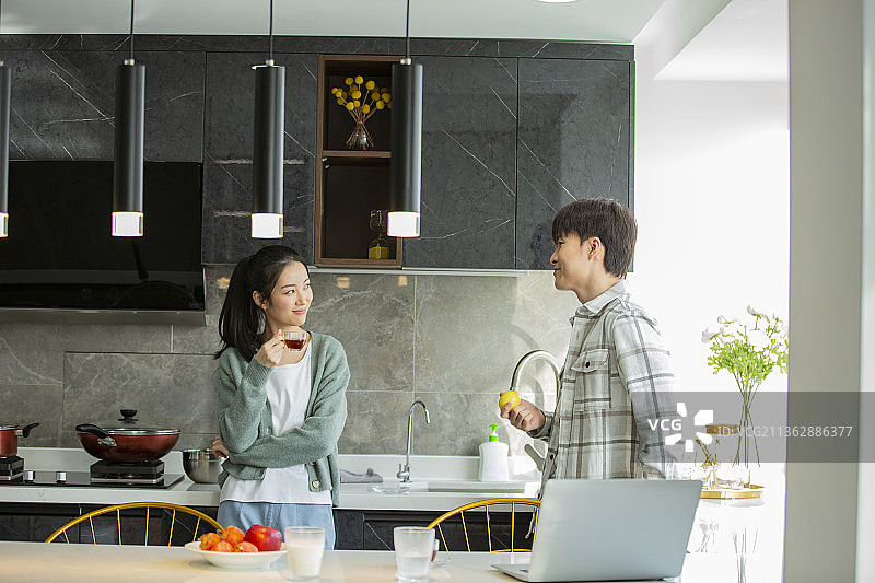 年轻情侣在开敞厨房喝咖啡休闲聊天图片素材