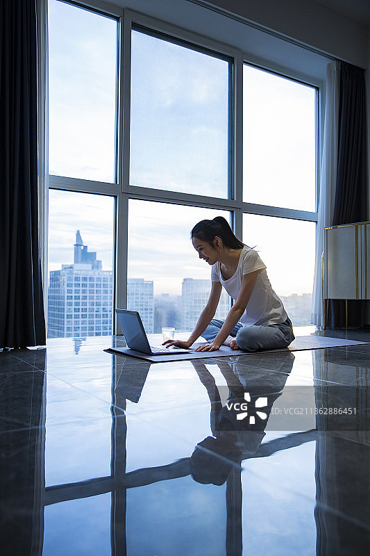 青年女子早晨在客厅使用笔记本电脑准备运动图片素材
