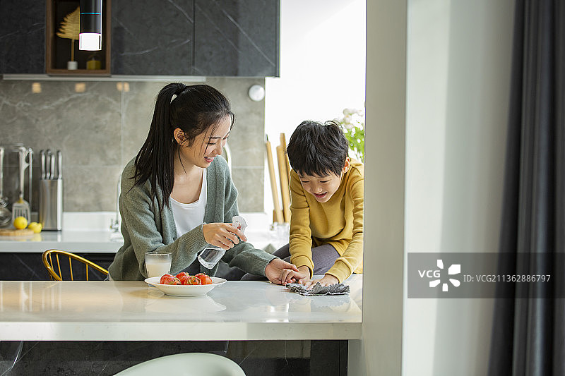 快乐母子在开敞厨房拿着喷壶和抹布打扫卫生图片素材