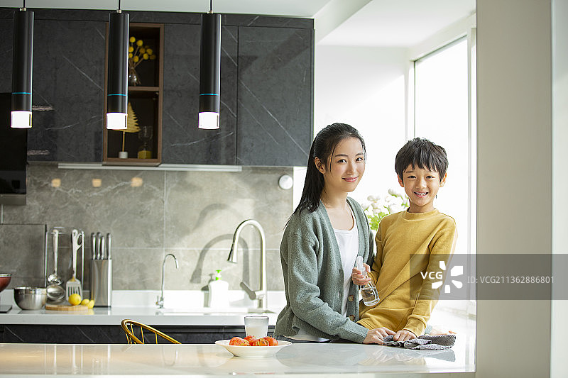 快乐母子在开敞厨房拿着喷壶和抹布打扫卫生图片素材