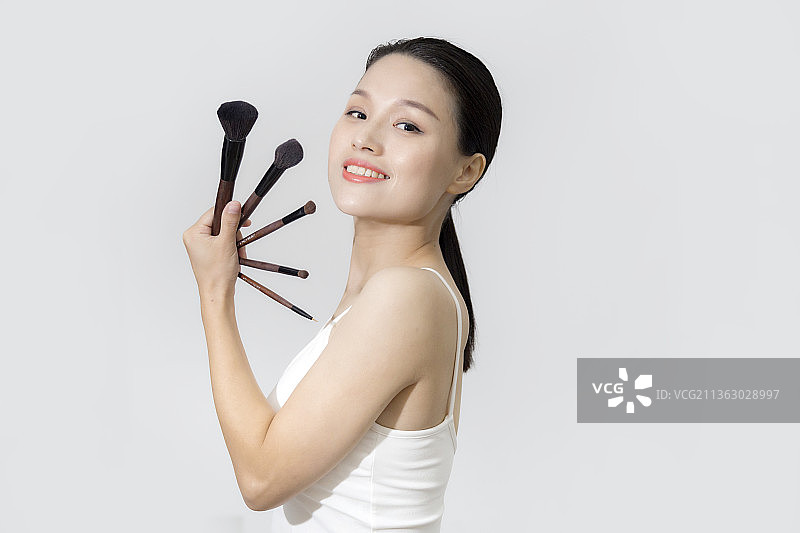 一个东方美女拿着化妆笔上半身特写图片素材