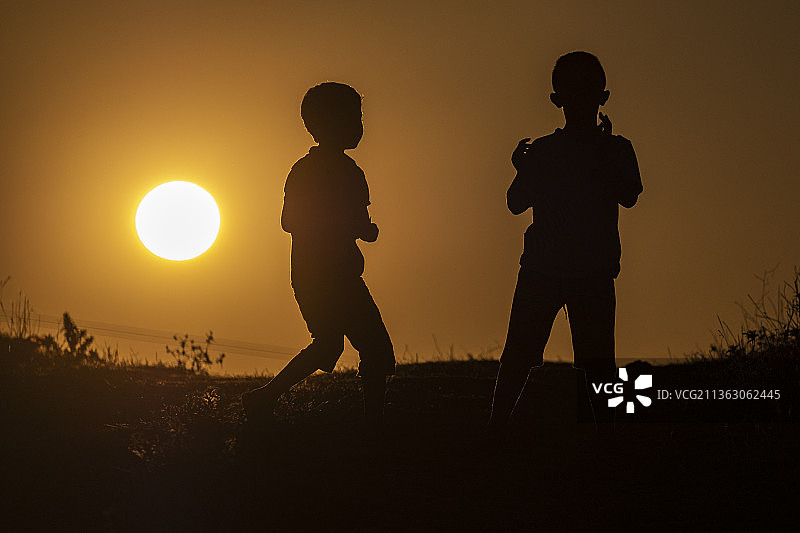 日落时分玩耍的两个孩子图片素材