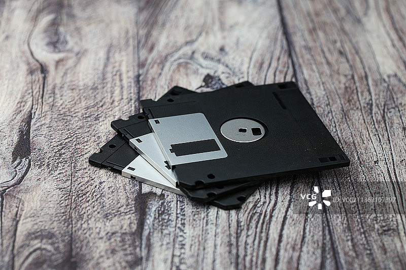 老式复古计算机软盘放在木纹背景上图片素材