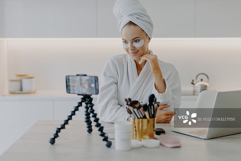 漂亮女人在家录制视频教程，使用美容垫图片素材