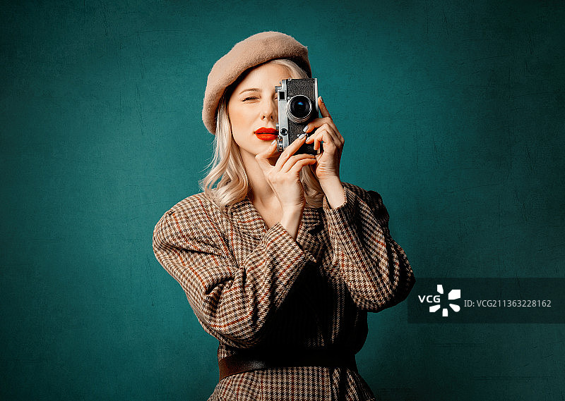 身穿英伦风夹克，手持复古相机的女人，背景为绿色图片素材