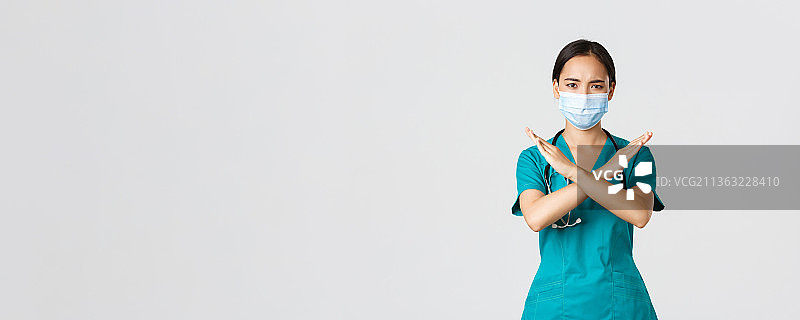 戴着外科口罩站在白色背景前的女子肖像图片素材