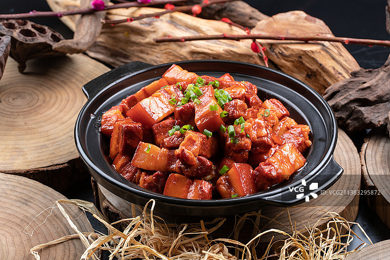 黑色砂锅装的锅仔红烧肉摆放在樟木砧板上图片素材