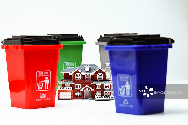 别墅房子模型放在四个垃圾分类垃圾桶前图片素材