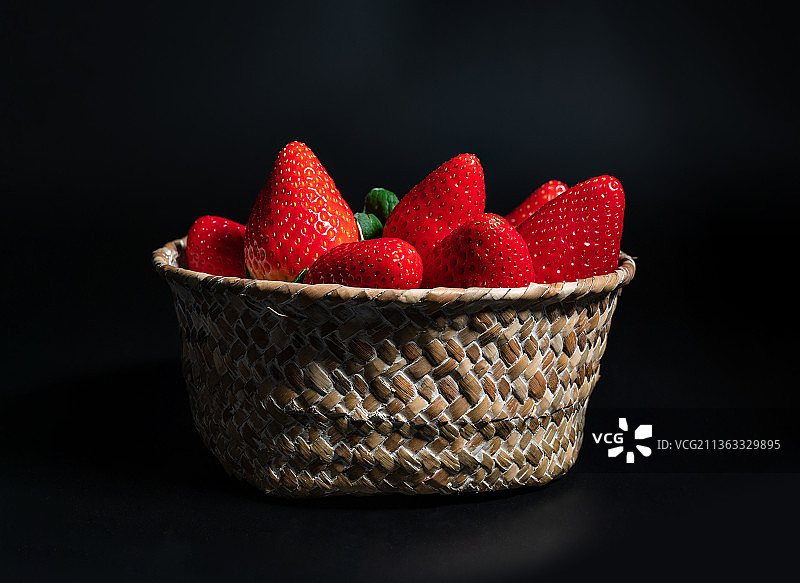 深色背景下的柳条筐中的新鲜草莓图片素材