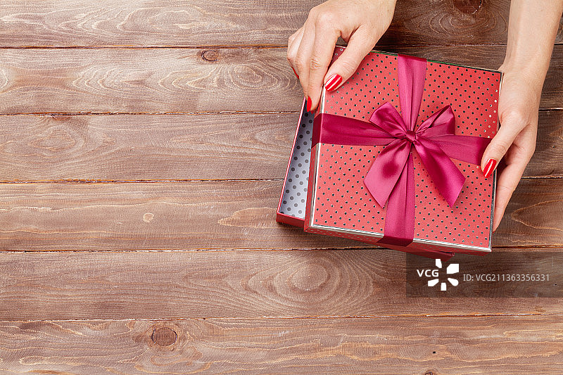 女人双手打开圣诞礼物，裁剪后的双手在桌子上拿着礼品盒图片素材