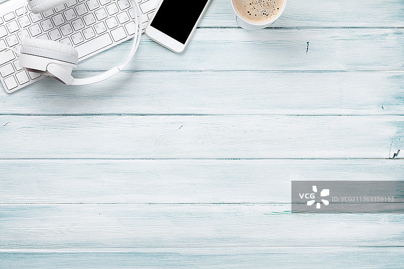 配有耳机、电脑、手机和咖啡的木制办公桌图片素材