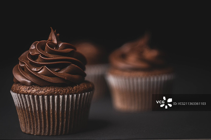 甜蜜的爱，黑色背景上的纸杯蛋糕特写图片素材