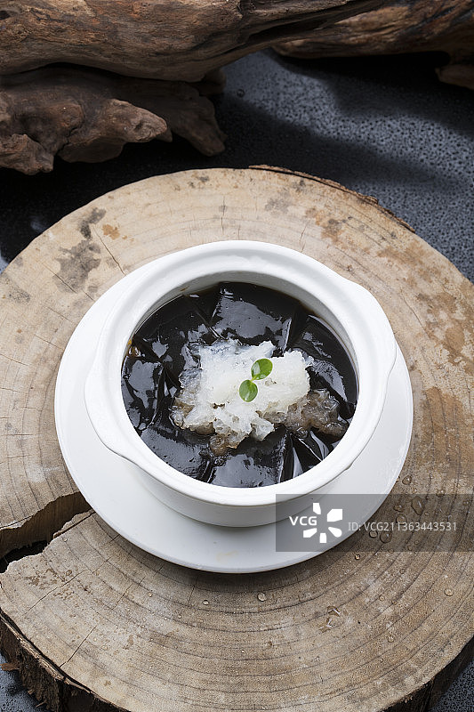 白色汤盅装的银耳龟苓膏摆放在樟木砧板上图片素材